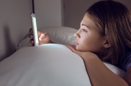 Une adolescente utilise son téléphone au lit.